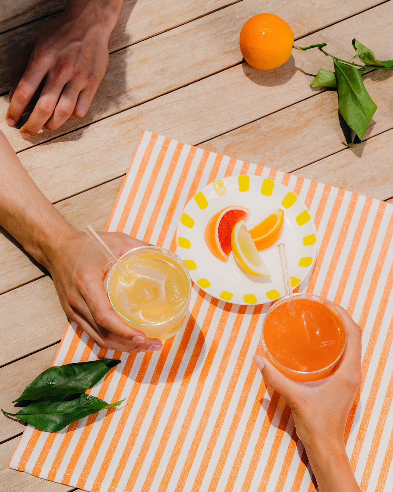 Set Bestseller: mani con drink rinfrescanti su tavolo estivo.