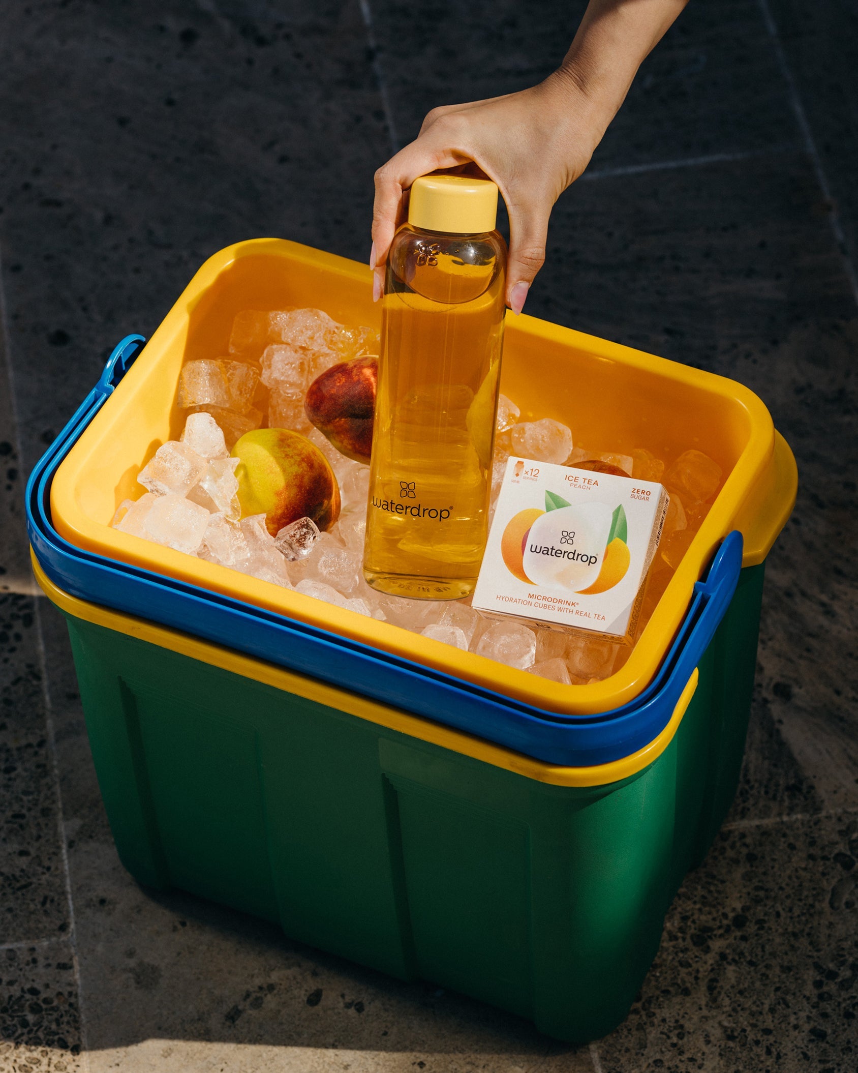 Set Bestseller: mano afferra bottiglia Waterdrop dal ghiaccio nel cooler.