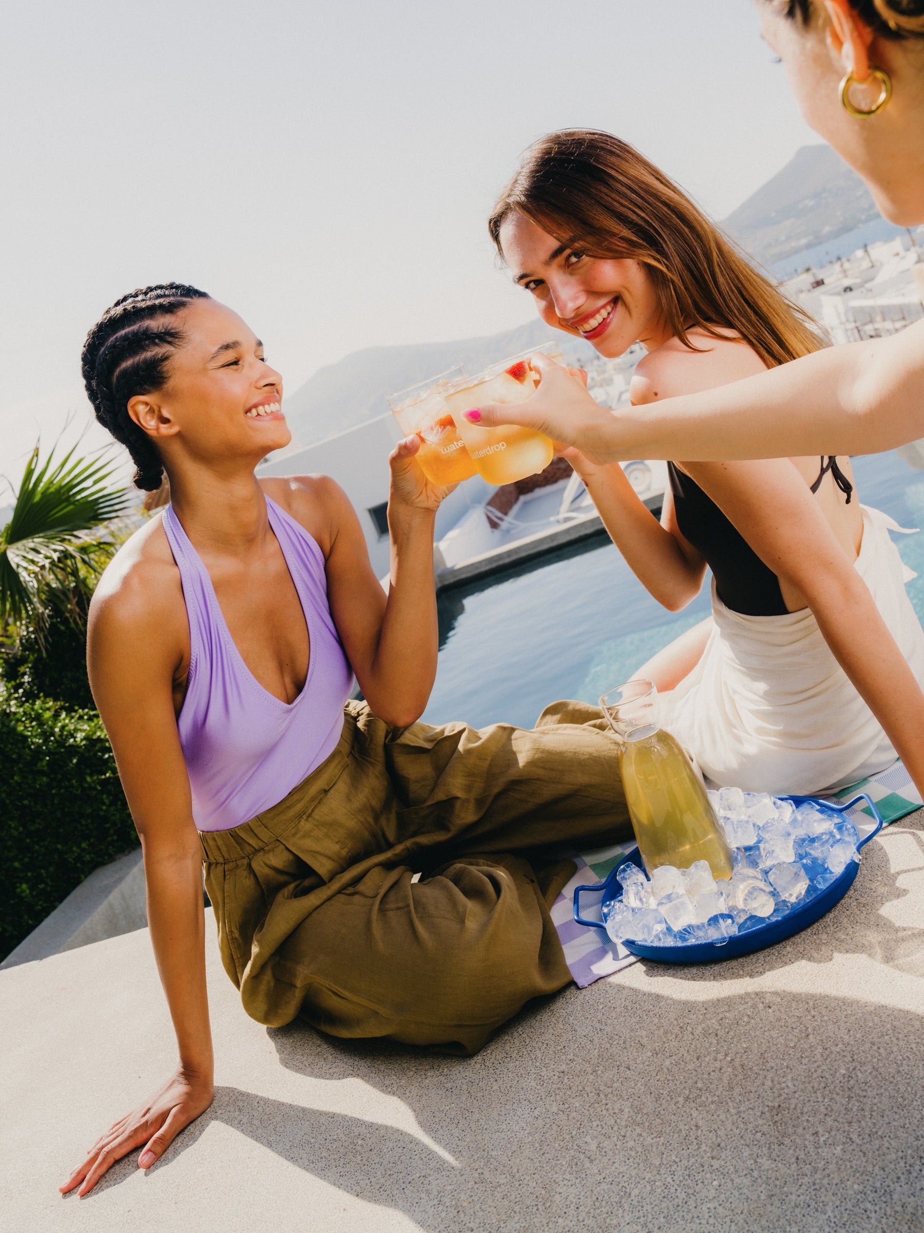 Set Bestseller: due donne brindano con bevande su un terrazzo soleggiato.