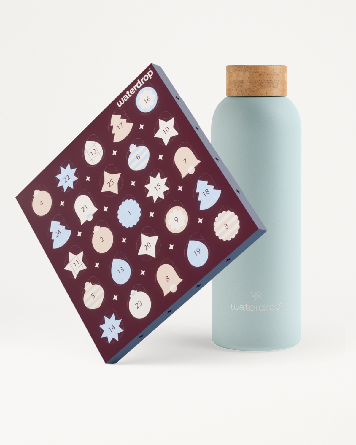 Bottiglia riutilizzabile azzurro chiaro con tappo in legno accanto a un calendario dell’avvento viola decorato con fiocchi di neve bianchi e azzurri.