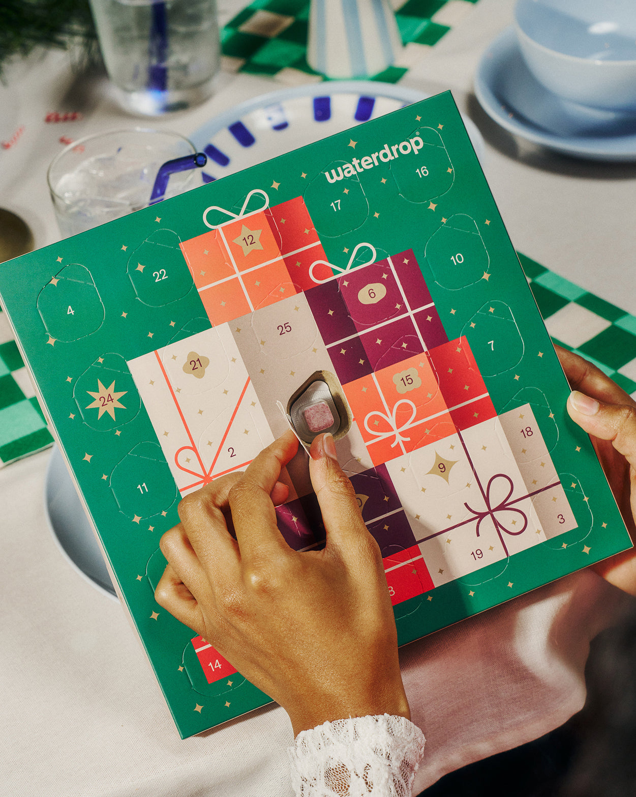 Calendario dell'Avvento Waterdrop, mani aprono finestrella rivelando cubetto microdrink.