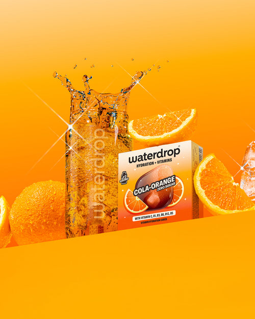 Bicchiere di COLA ORANGE con cubetti di ghiaccio e cubetti vitaminici.