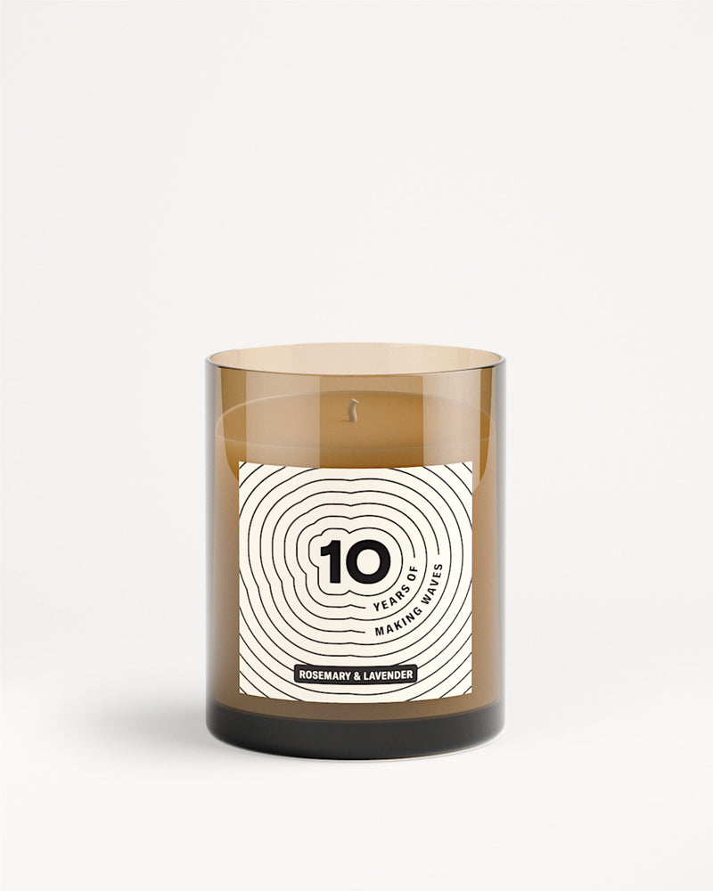 Vaso di vetro marrone per candela con etichetta bianca e motivo a cerchi concentrici.
