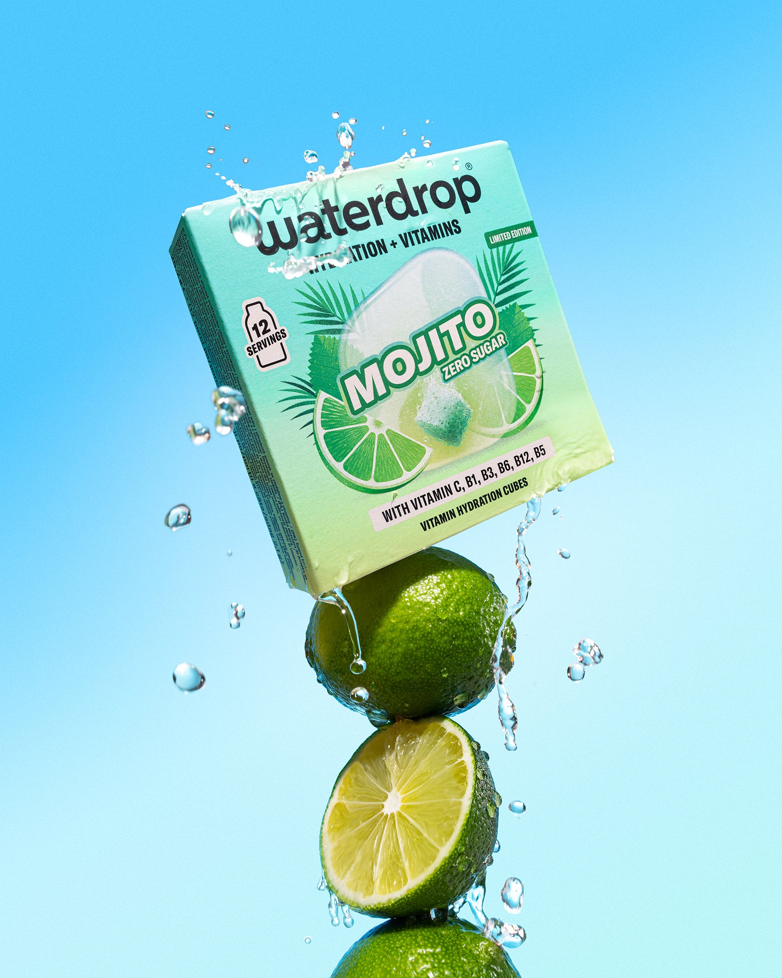 Lime impilate sotto una scatola verde menta di bevanda con schizzi d'acqua sullo sfondo azzurro.