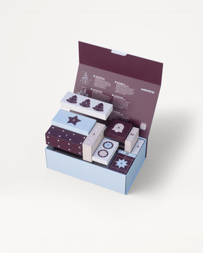 Scatola regalo a tre livelli azzurra con coperchio viola aperta per rivelare diverse piccole scatole decorative coordinate.