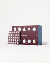 Calendario dell'Avvento con pannelli viola e ornamenti bianchi, mostrato con una scatola interna blu.