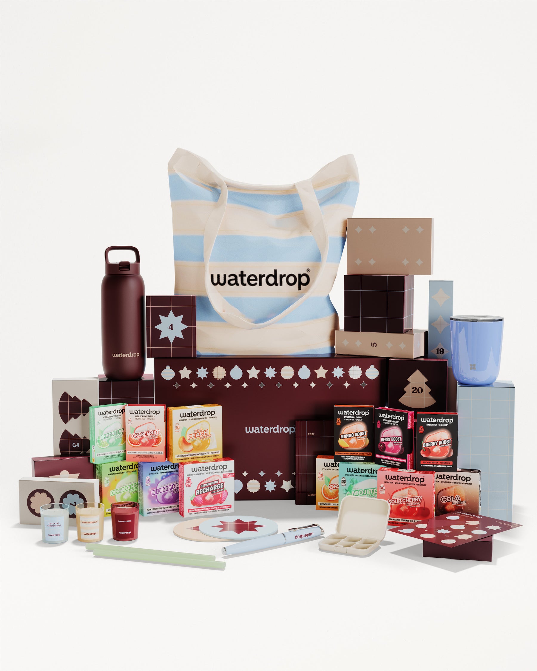 Set regalo con prodotti in scatole e contenitori vari, disposti intorno a una borsa a righe.
