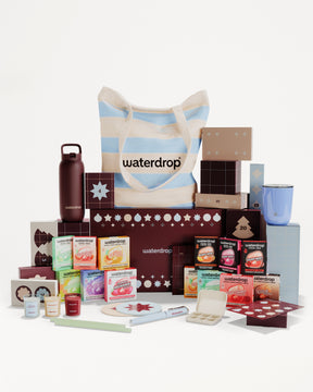 Set regalo con prodotti in scatole e contenitori vari, disposti intorno a una borsa a righe.