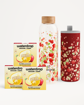 Assortimento di prodotti Waterdrop: due scatole gialle, una bottiglia di vetro alta con pezzi di frutta e uno shaker rosso macchiato.