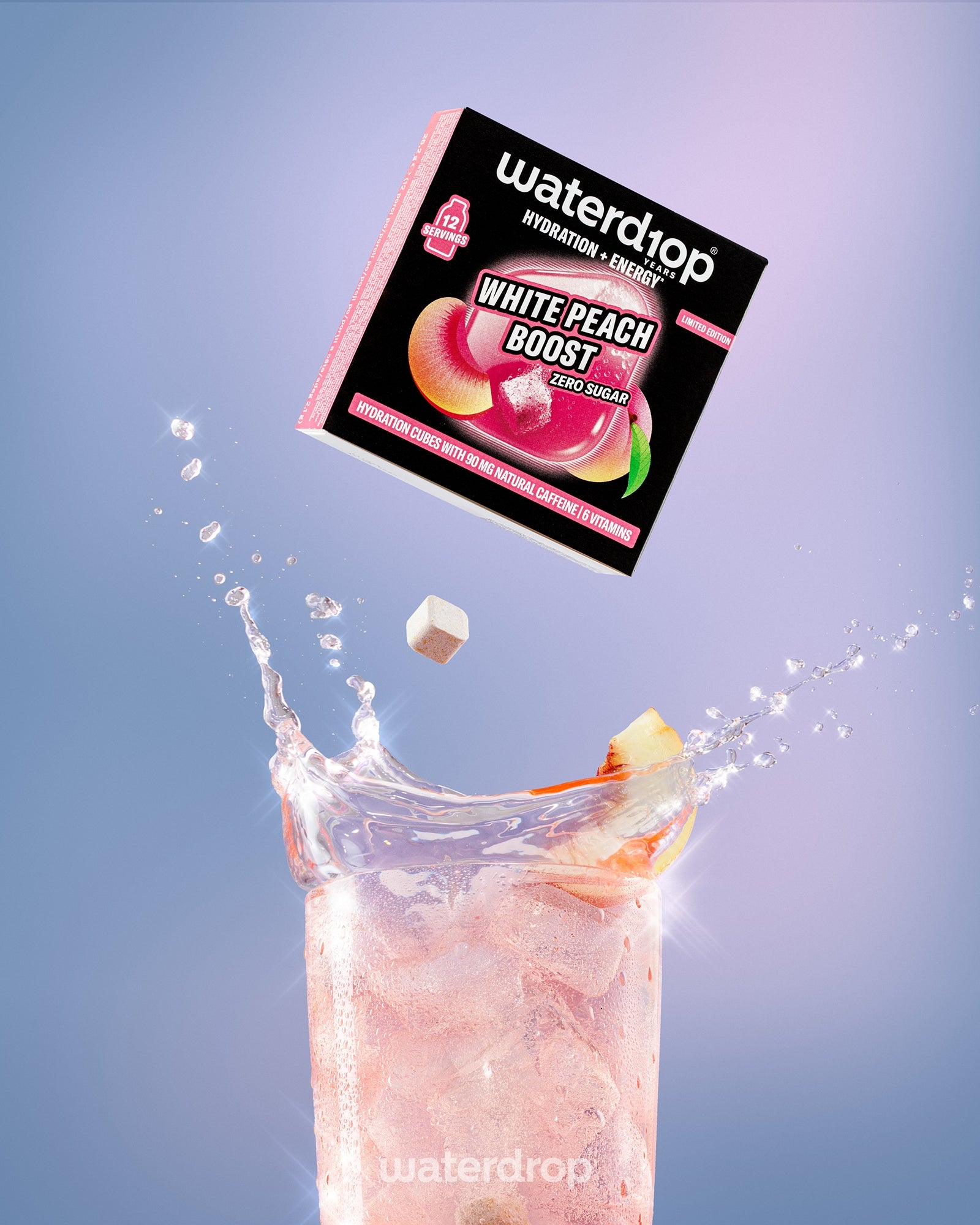 Scatola del mix per drink White Peach Boost sopra un bicchiere alto con bevanda rosa e ghiaccio.