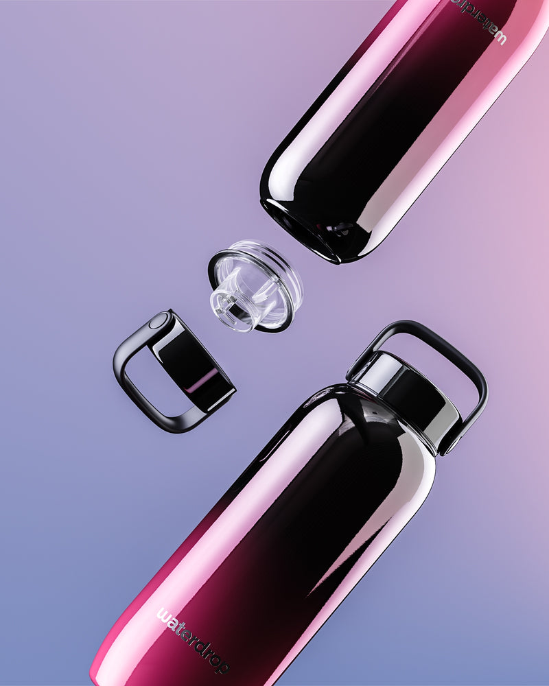 Due bottiglie d'acqua in acciaio inossidabile con gradiente rosa e viola, tappi rimossi, disposte diagonalmente.