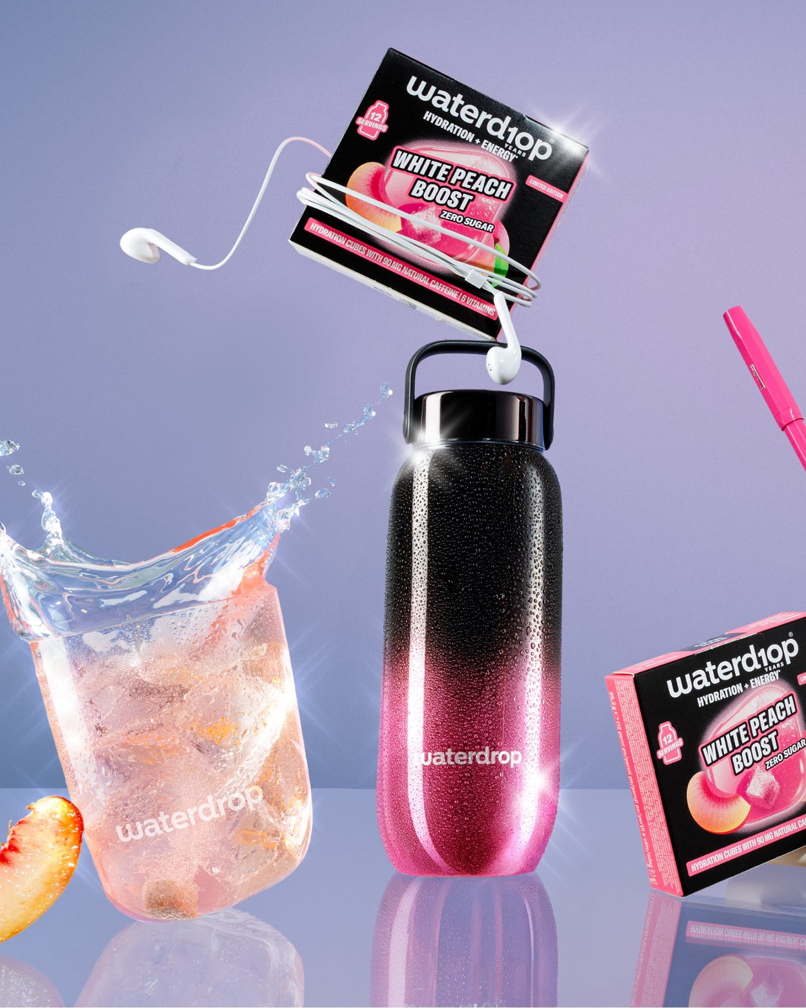 Bottiglia riutilizzabile con gradiente rosa-nero e maniglia ad anello, pacchetti di gusto collegati, bicchiere di ghiaccio con spicchio di pesca e accessorio cannuccia rosa.
