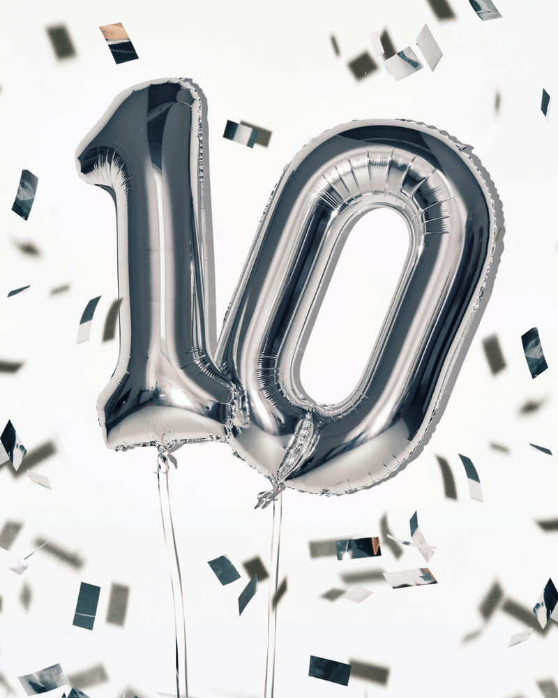 Balloon in foglio argentato a forma del numero 100 con corde, circondati da confetti.