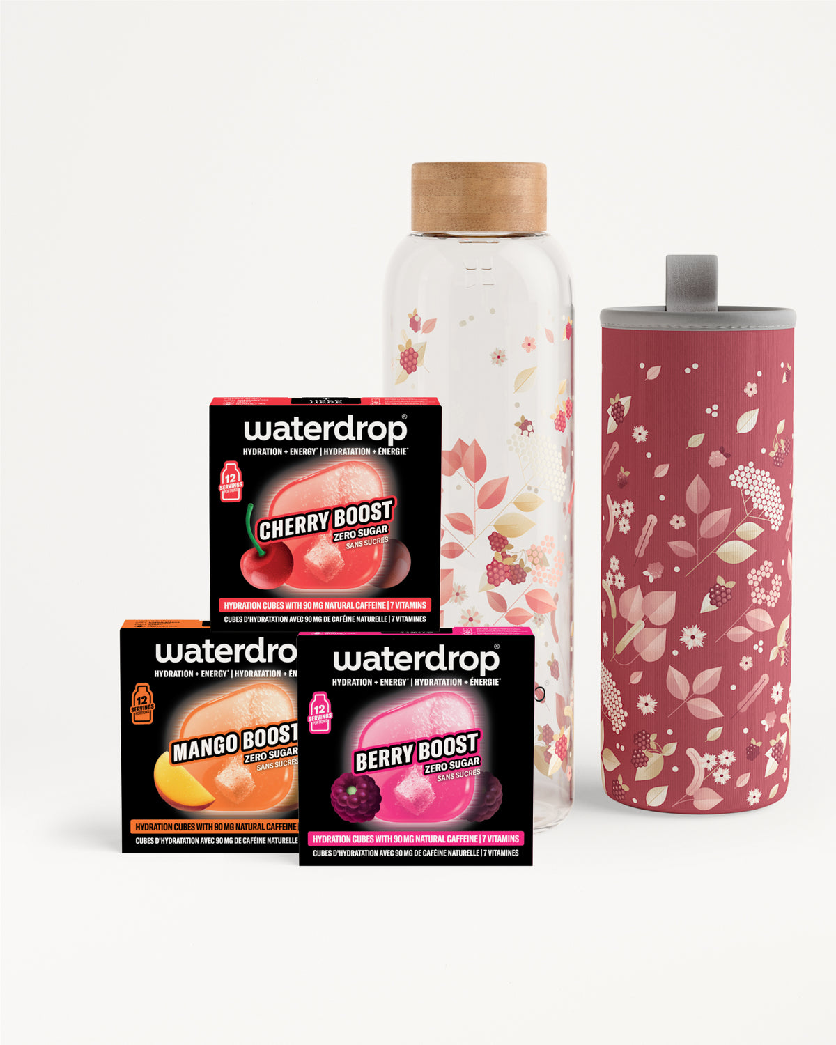 Assortimento di tre bustine Flavor Boost accanto a una bottiglia di vetro trasparente con tappo in legno e un tumbler alto rosa con motivo floreale.