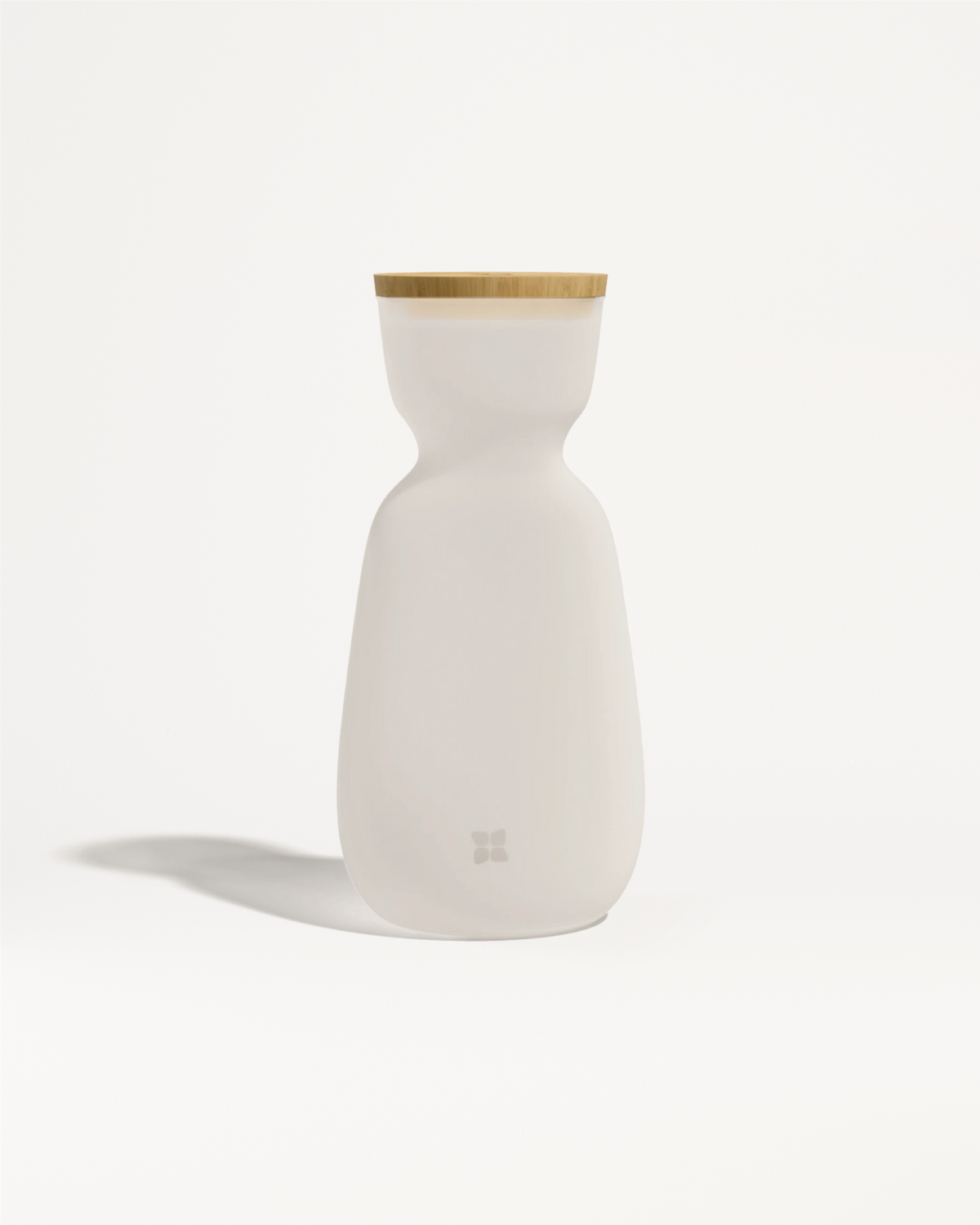 Bottiglia in ceramica bianca con coperchio in legno chiaro e corpo dalla forma liscia e curva.