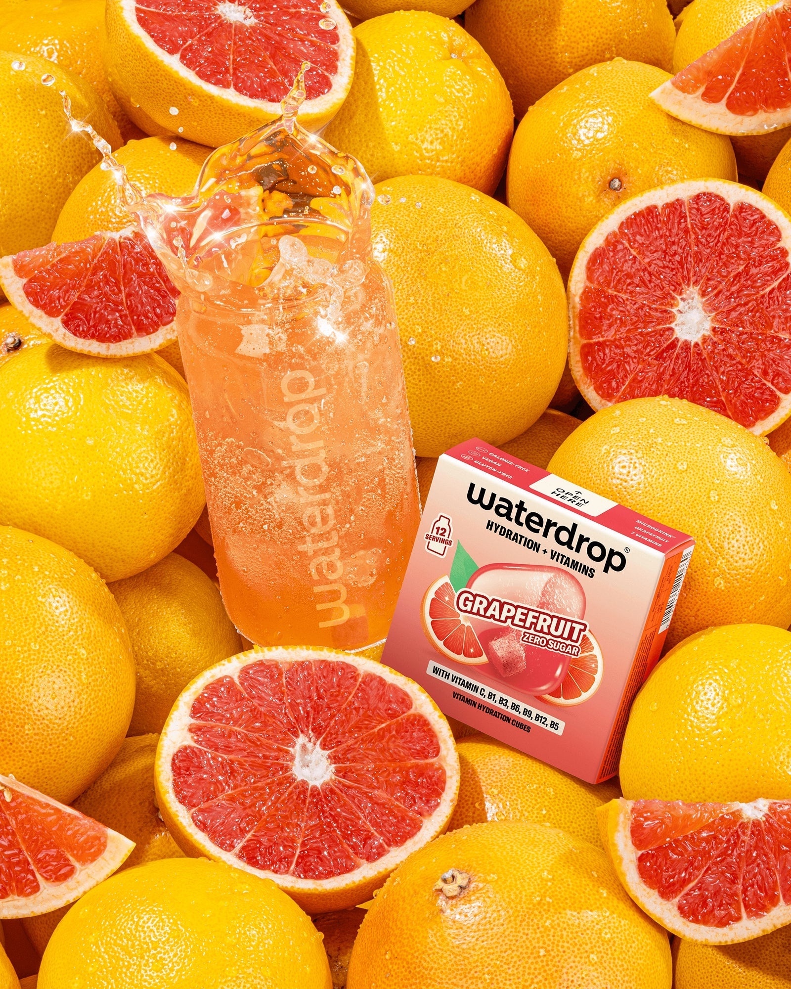 Assortimento di pompelmi con una bottiglia di bevanda al pompelmo rosa e una piccola scatola tra la frutta.