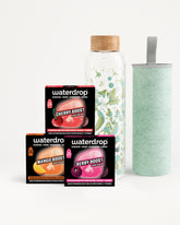 Set di tre confezioni Waterdrop Flavor Boost con una bottiglia in vetro con tappo in legno e un tumbler verde chiaro.