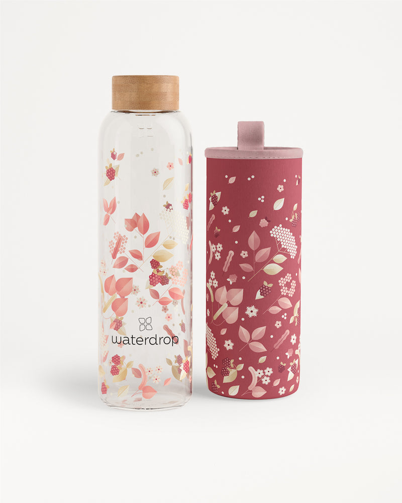 Due bottiglie d'acqua con motivo floreale, una trasparente con tappo in legno e l'altra rosa con tappo abbinato.
