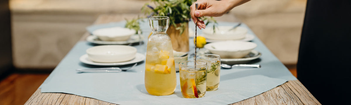 Tavolo da pranzo allestito con una caraffa e bicchieri e un motivo centrale.