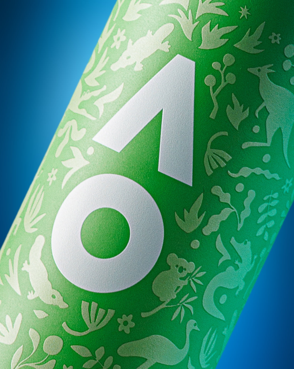 Primo piano di una bottiglia cilindrica verde con grande emblema geometrico bianco e silhouette decorative bianche su sfondo blu.