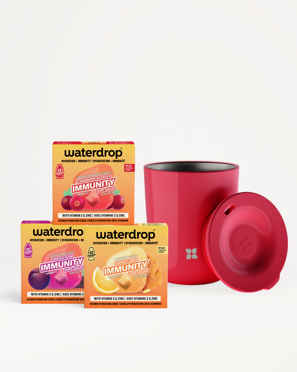 Tre confezioni colorate di bustine vitaminiche poste accanto a una bottiglia cilindrica rossa con tappo abbinato.