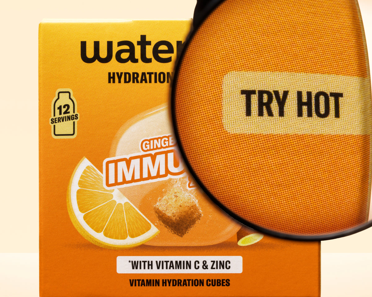Scatola arancione con grafica al limone e ingranditore sovrapposto, cubi di idratazione vitaminici.