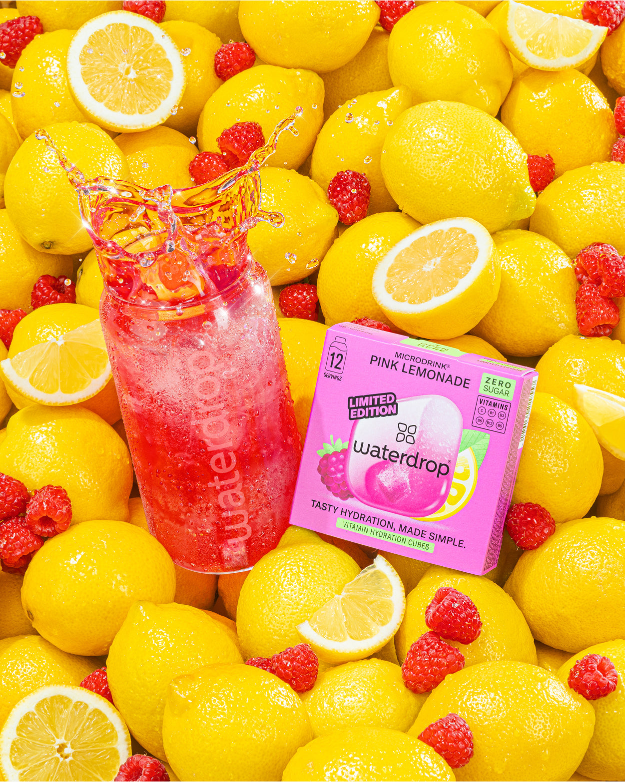 Bottiglia di limonata rosa e confezione Waterdrop tra limoni gialli.
